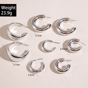 Close-up of three sizes of thick silver C-shaped hoop earrings with a polished finish