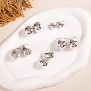 Detail of five pairs of silver geometric stud earrings on a white plaster tray