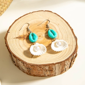Ocean shell earrings with blue beads and pearls on wooden pedestal background