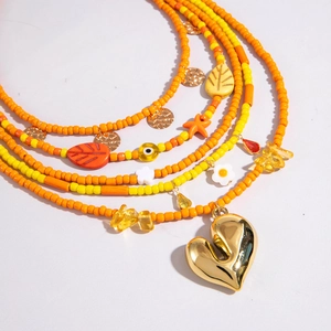 Detail of multi-layered beaded necklace with gold heart pendant and colorful charms