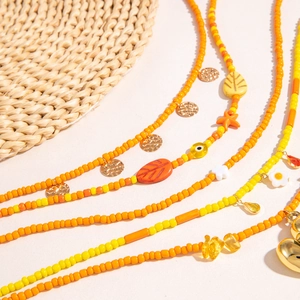 Detail of bohemian necklaces with yellow beads, daisies, and golden heart charms