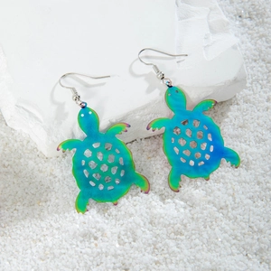Detail of sea turtle drop earrings with gradient metallic finish on white pebbles