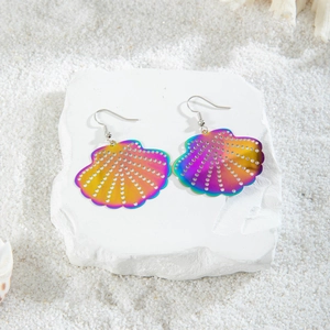 Rainbow gradient shell earrings with hollow metal design on white beach sand backdrop