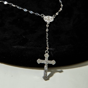 Detailed close-up of a silver Y-necklace featuring an engraved cross and religious medal