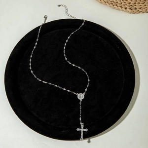 Detailed view of silver cross pendant with faux pearl necklace on black velvet pad