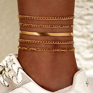 Detalle de set de cinco tobilleras boho doradas con cadenas Figaro y de serpiente en el tobillo