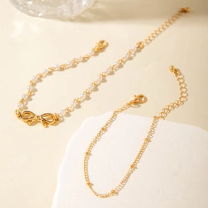 Detalle del conjunto de tobilleras bohemias con perlas blancas y colgante de mariposa