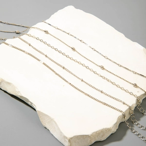 Detalle de cinco tobilleras bohemias plateadas sobre un soporte de piedra blanca