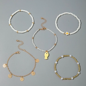 Detalle de cinco tobilleras bohemias con cuentas, discos dorados y colgantes de flores