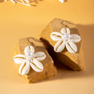 Detalle de pendientes de flores de concha con perla sobre piedras naturales