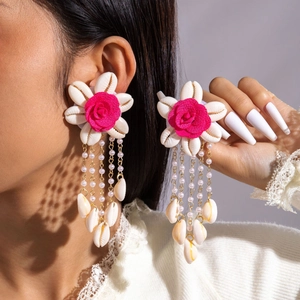 Detalle de pendientes de flores de concha hechos a mano con rosa de tela y borlas doradas