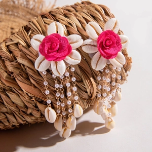 Detalle de pendientes bohemios de flores con rosas rosas y borlas de cadena dorada