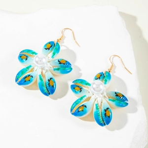 Detalle de pendientes de concha en forma de flor con estampados de tortuga y perla central