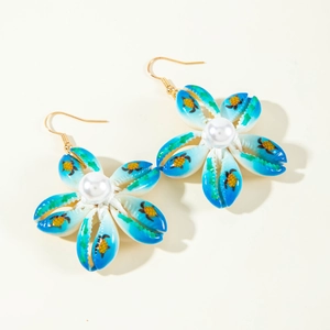 Detalle de pendientes de flores de concha con dibujos de tortugas azules y perlas