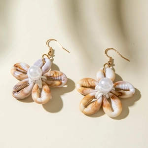 Detalle de pendientes de flores de concha hechos a mano con perla y ganchos oro
