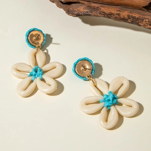 Detalle de pendientes de flor de concha hechos a mano con cordón azul y pernos dorados