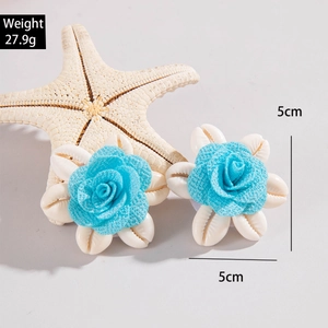 Detalle de pendientes de flores de tela azul hechos a mano con conchas blancas y medidas