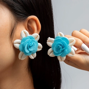 Primer plano detallado de pendientes de flores de concha con rosas azules y nácar natural