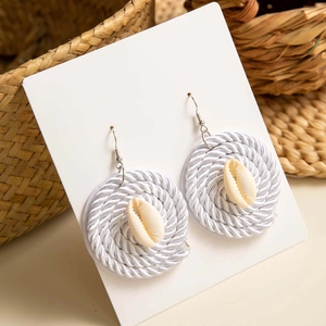 Detalle de pendientes tejidos a mano con conchas naturales y ganchos plateados