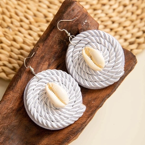 Detalle de pendientes de flores de concha hechos a mano con cordón sobre madera vintage