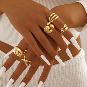 Close-up of five irregular gold geometric rings set with stacked styling on model hand