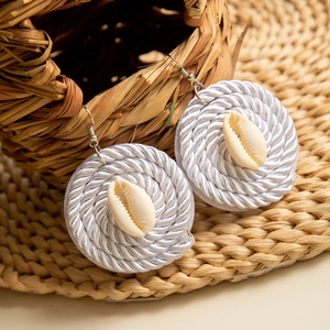 Detalle de pendientes de flores de concha hechos a mano con textura tejida estilo playa