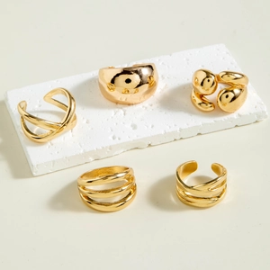 Detailed view of five-piece gold irregular geometric rings set on a white stone base