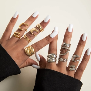 Detail of irregular organic gold and silver rings worn on model against beige background