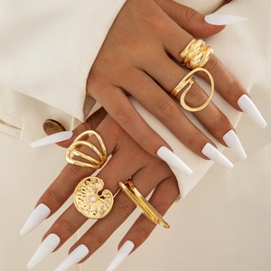 Close-up of a 5-piece gold ring set featuring irregular textures and a white pearl accent