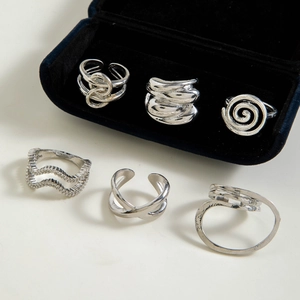 Detailed view of six irregular silver geometric rings with polished metallic finish