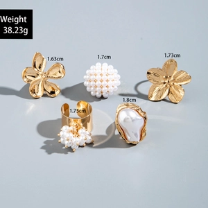 Detailed flat lay of a five-piece gold ring set with irregular pearls and floral designs