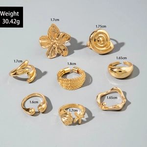 Macro view of 8-piece gold ring set showing floral, shell, and starfish texture details