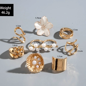 Detailed view of an 8-piece gold vintage ring set with pearls and enamel flower charms