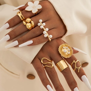 Detailed view of layered gold rings with pearls and enamel flower on a model hand