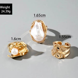 Macro shot of gold baroque pearl rings set with detailed hammered metal textures