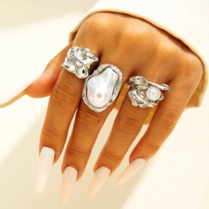 Macro detail of irregular lava texture rings with baroque pearls on model's hand