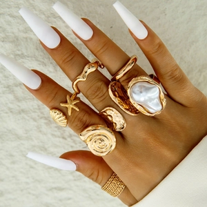 Golden baroque pearl ring set featuring starfish and seashell designs on model hand