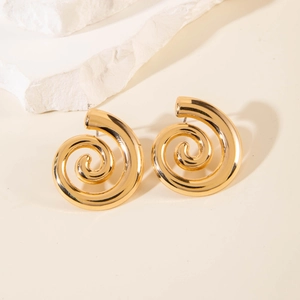 Close-up of golden spiral stud earrings with geometric swirl design on white stones