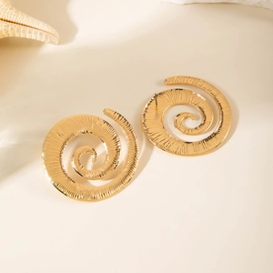 Detailed macro view of gold spiral earrings with textured radial engravings and chic finish