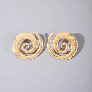 Macro detail of golden spiral stud earrings with radial textured metallic pattern