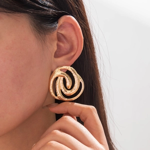 Macro shot of gold geometric earrings with hammered texture on a female model