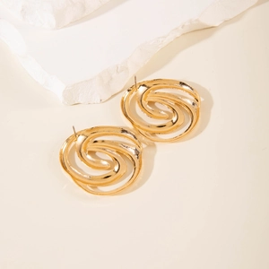 Detailed close-up of golden spiral earrings with hammered metal texture on stone