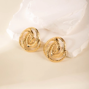 Macro detail of gold hammered metal geometric earrings on a natural stone base