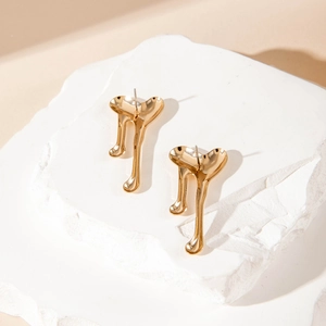 Detailed view of heart-shaped lava textured gold earrings on a white stone pedestal