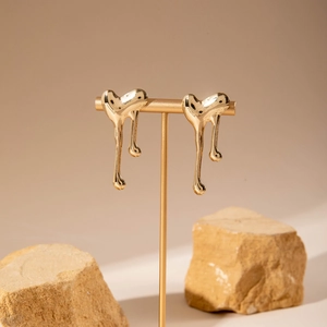 Detailed view of liquid heart-shaped gold earrings with high-polish metallic finish