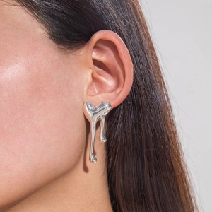 Close-up of silver liquid metal earrings with a molten lava fluid drop design