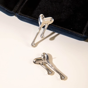 Macro detail of silver fluid-melt heart earrings with high-polish metallic finish
