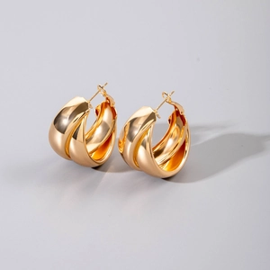 Macro view of gold geometric hoop earrings with polished finish and layered stripe design