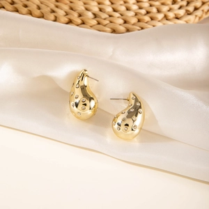 Detail of gold teardrop earrings with crystal pavé on silk fabric texture