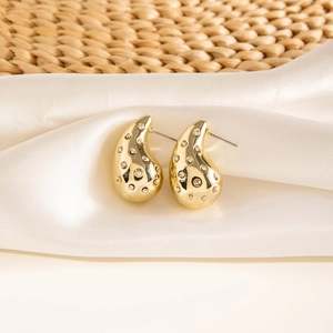 Detailed view of gold teardrop earrings with embedded crystals on textured fabric